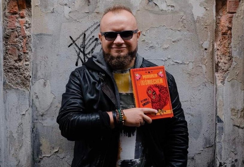 Autor książki trzymający w dłoniach lekturę.