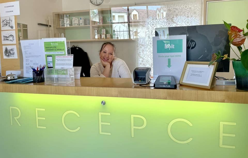 Uczennica za hotelową recepcją podświetloną na zielono.