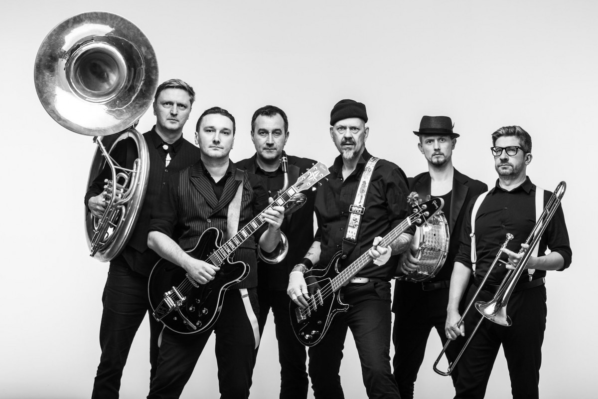 Grafika przedstawiająca członków zespołu Cyrk Deriglasoff na szarym tle stoi sześciu ubranych w czarne ubrania mężczyzn każdy z nich trzyma instrument muzyczny