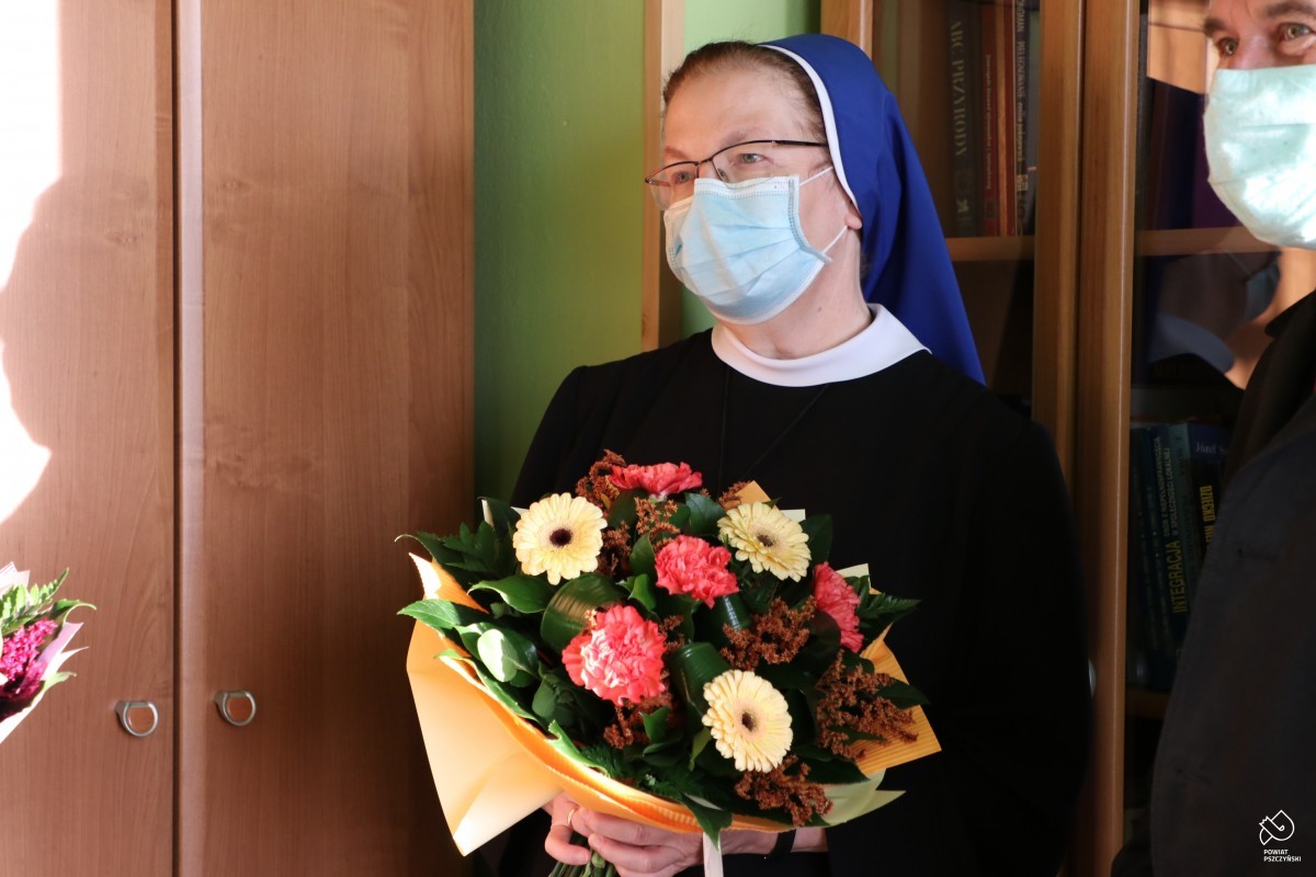 Zdjęcie przestawia siostrę zakonną, która w dłoniach trzyma kwiaty.