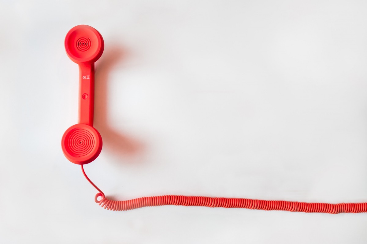 Czerwona słuchawka z telefonu stacjonarnego na białym tle.