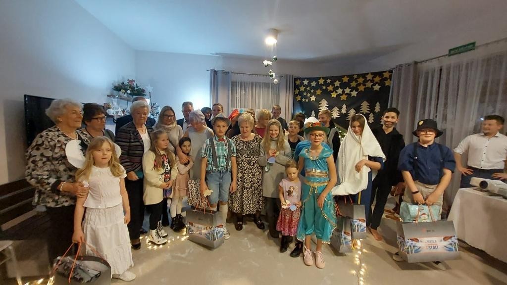 Grupa dzieci z domu dziecka ubrana w świąteczne stroje i goście z Niemiec.
