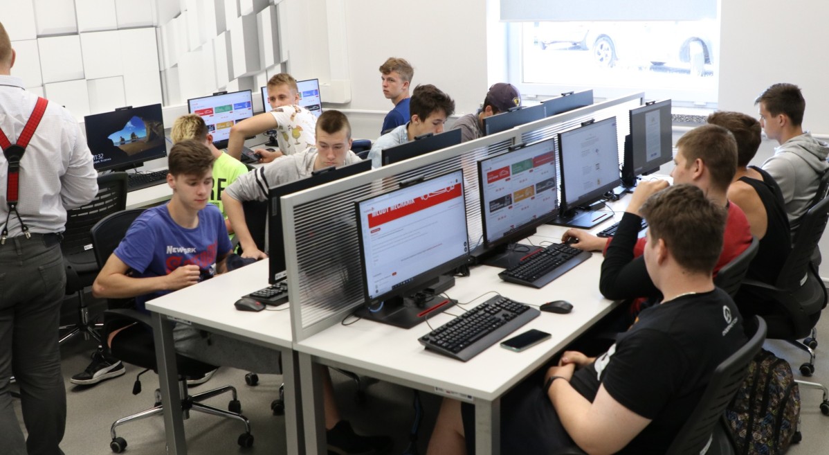 W klasie komputerowej przy stanowiskach komputowych siedzą uczniowie. To młodzi chłopcy, którzy biorą udział w konkursie.